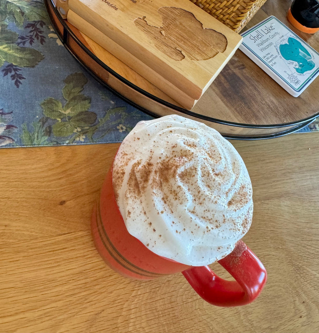 Maple Sugar Fika Spice sprinkled on a cup of hot coffee topped with a enormous pile of whipped cream. 